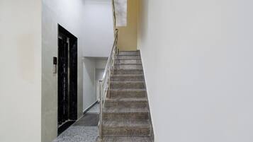 Escadaria com corrimão metálico que dá acesso a um elevador.