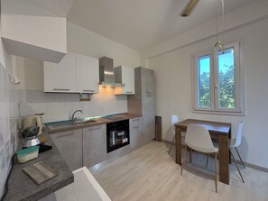 Eine moderne Küche mit weißen Schränken, einem eingebauten Ofen und einem Essbereich mit einem Holztisch und Stühlen.