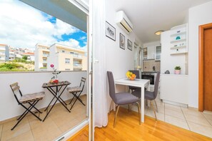 En kompakt bolig med balkon, spiseplads og tekøkken.