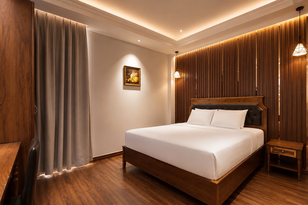 A hotel room with a wooden bed, a nightstand, a lamp, and a curtain.