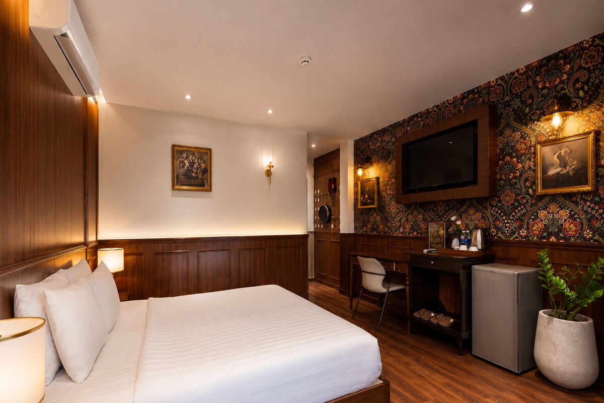 A hotel room with a bed, desk, chair, television, and a decorative wall.
