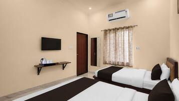 A hotel room with two beds, a flat-screen TV, an air conditioning unit, a small shelf with cups and a kettle, and a window with curtains.