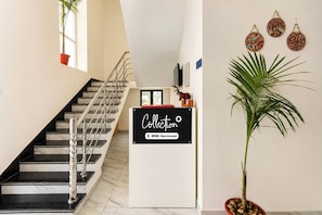 A staircase with a handrail, a sign reading 'Collection OYO-Serviced', and a potted plant.
