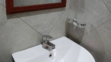 A bathroom with a white sink, a mirror with a wooden frame, and tiled walls.