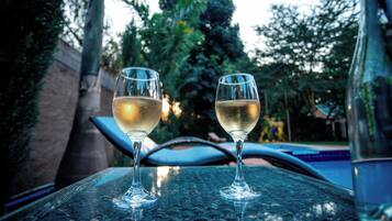 Two glasses of white wine on a glass table with a pool in the background.
