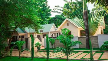 A residential property with a well-maintained garden, a paved driveway, and a two-story house with a green roof.