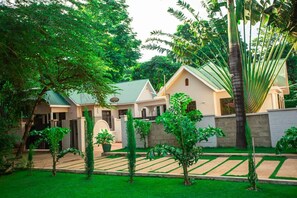 A residential property with a well-maintained garden, a paved driveway, and a two-story house with a green roof. - Tranquil 2-bedroom apartment with AC in Moshi (Kilimanjaro Region)