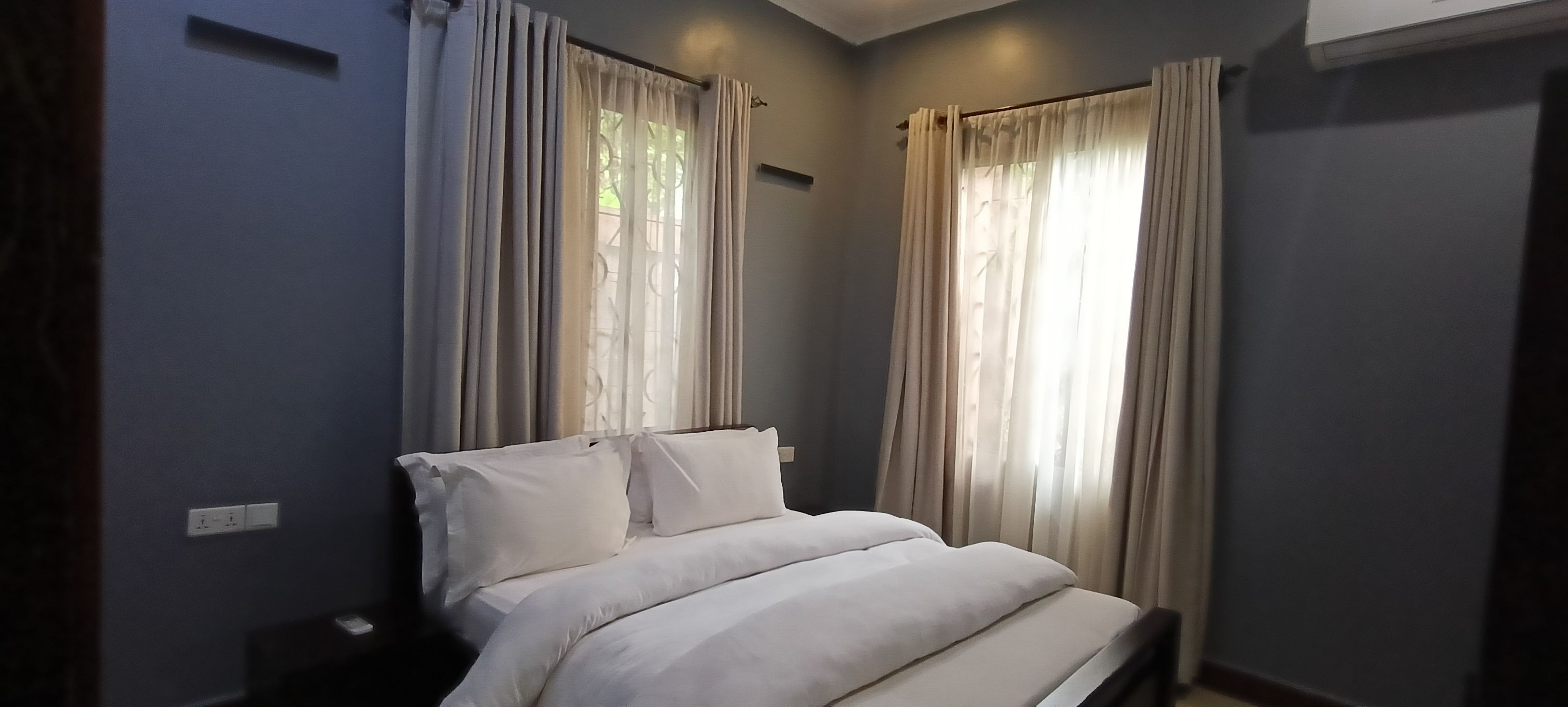 A bedroom with a bed, curtains, and a window.