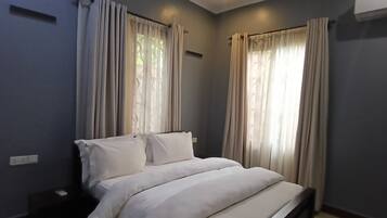 A bedroom with a bed, curtains, and a window.