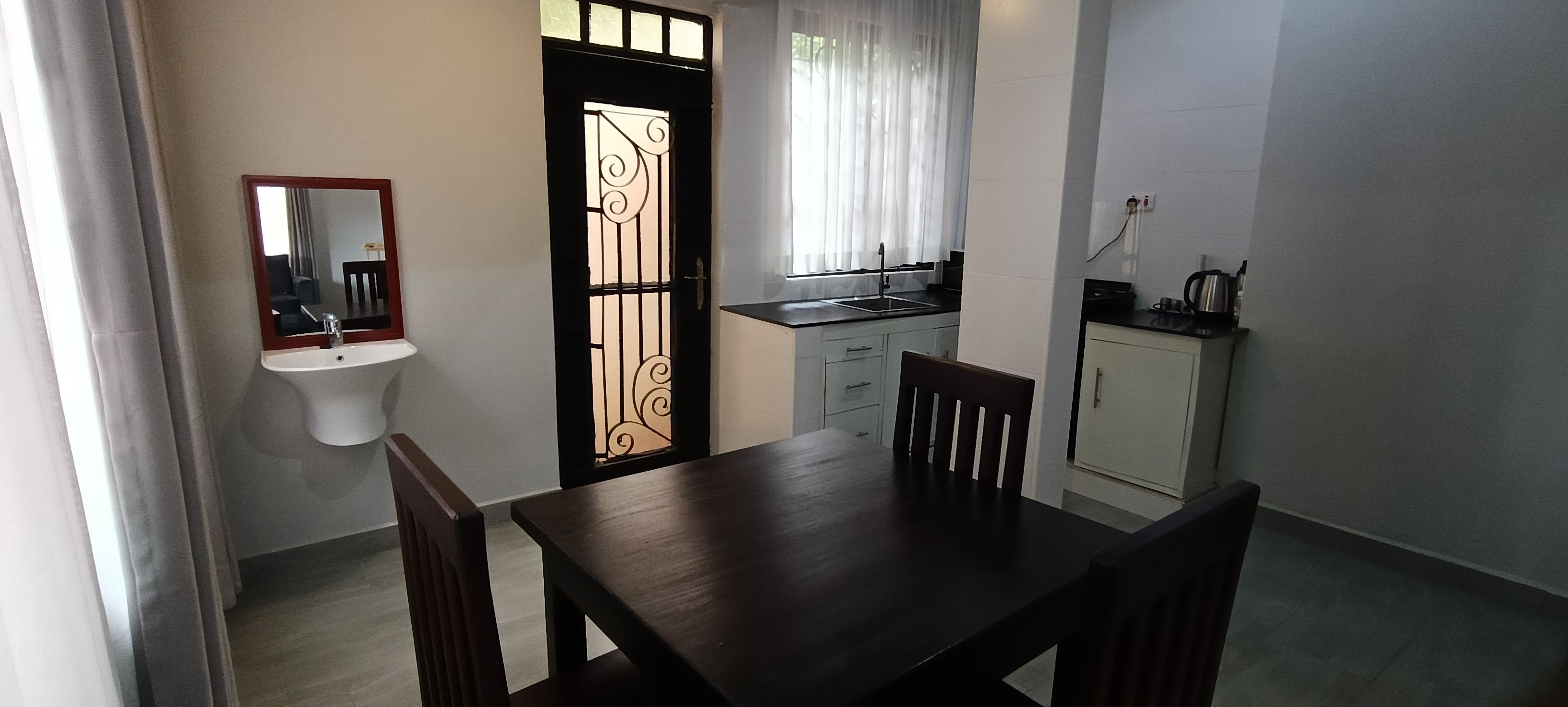 A compact kitchen with a sink, a dining table with chairs, and a cabinet.