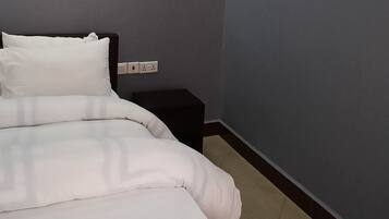 Une chambre à coucher comprenant un lit, une table de chevet, un appareil de climatisation et un luminaire fixé au mur.