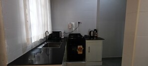 A compact kitchenette with a microwave, stove, and a small cabinet. - Tranquil 2-bedroom apartment with AC in Moshi (Kilimanjaro Region)