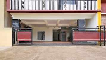 A building entrance with a gated driveway, a balcony with decorative railings, and a door leading into the building.
