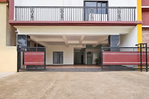 A building entrance with a gated driveway, a balcony with decorative railings, and a door leading into the building. - Super Hotel O Infocity Square Road (Bhubaneshwar)