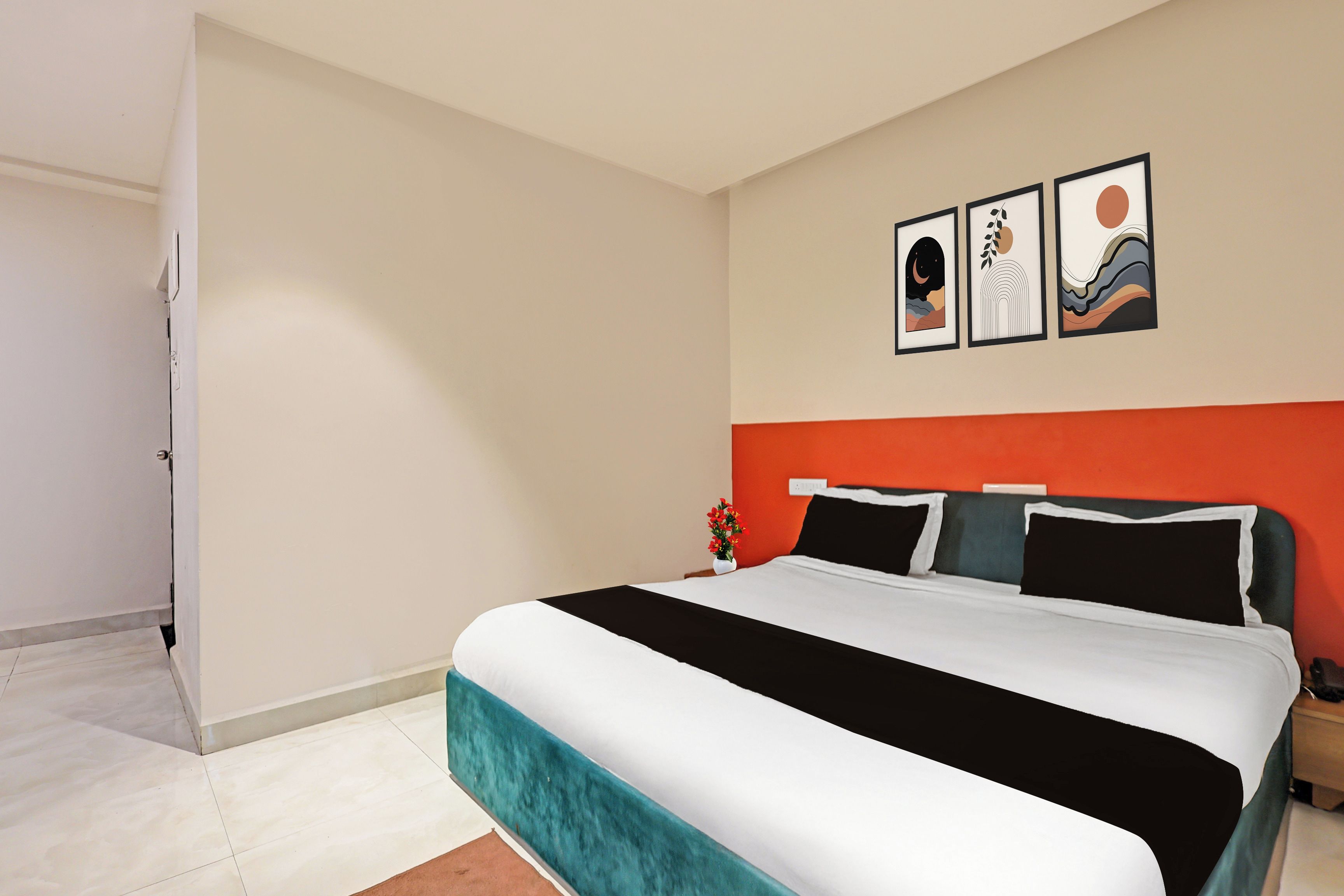 Un dormitorio con una cama, una mesita de noche, una pared con tres cuadros enmarcados y una puerta.
