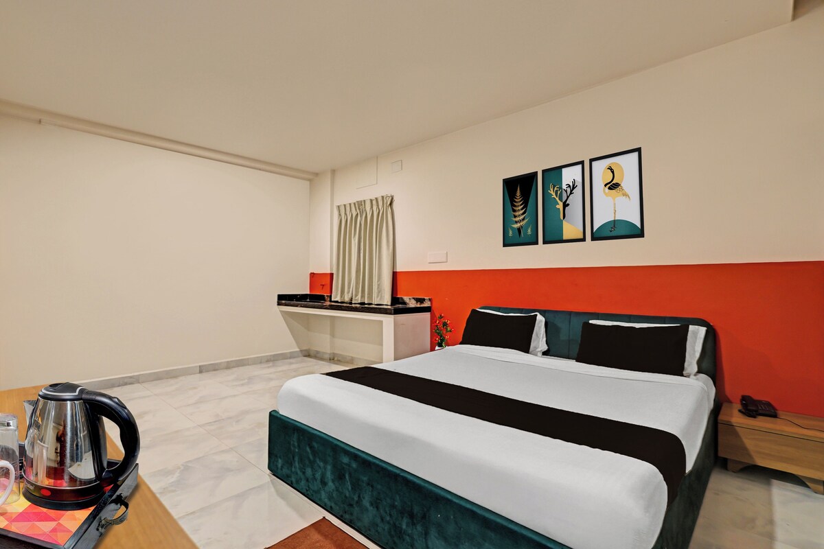 Una habitación de hotel con cama, escritorio, hervidor de agua y cuadros en la pared.