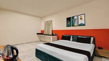 Ein Hotelzimmer mit Bett, Schreibtisch, Wasserkocher und Bildern an der Wand.