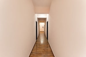 A narrow, well-lit hallway with wooden flooring and plain walls, leading to a door at the end. - Super Hotel O Infocity Square Road (Bhubaneshwar)