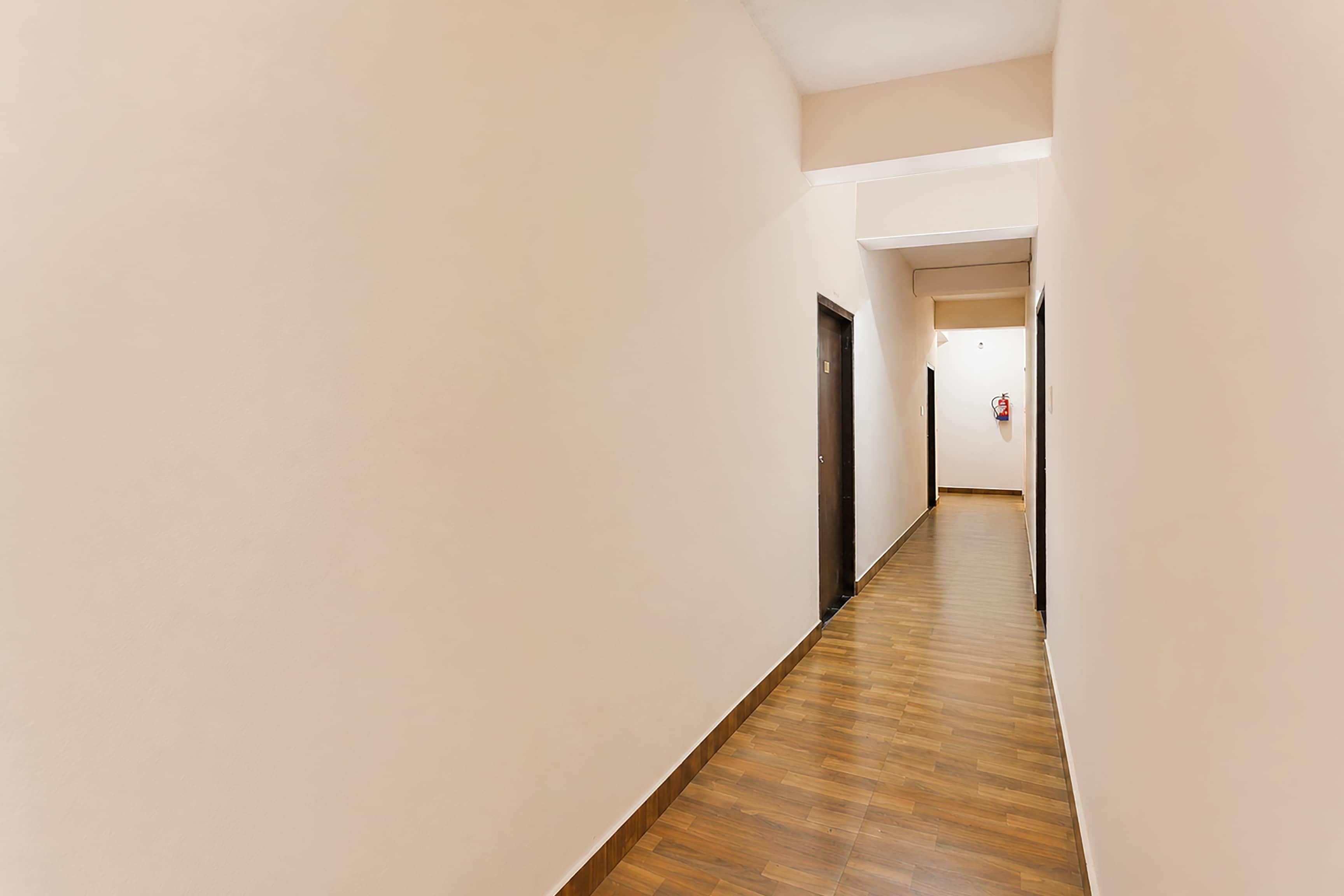 A corridor with wooden flooring and plain walls, leading to a door at the end.
