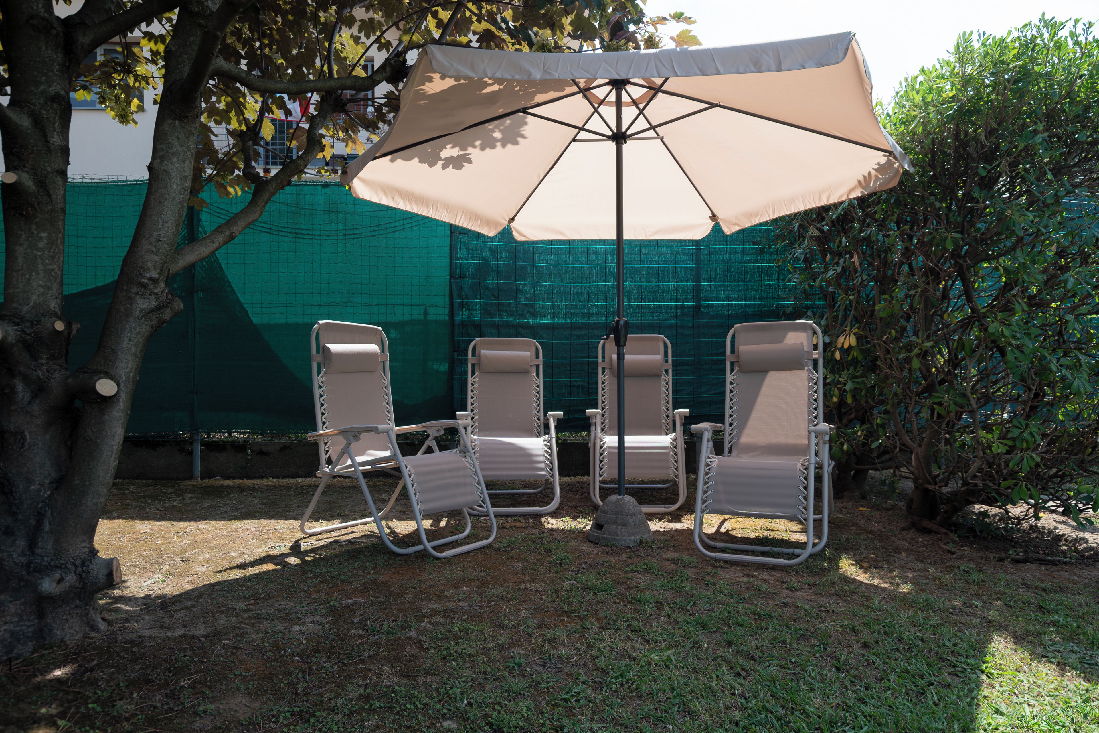 A patio area with four lounge chairs and a large umbrella.