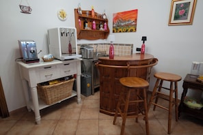 A compact kitchen with a coffee machine, a toaster, and a sink. There are two stools and a small table with a lamp. - B&B Villa Elena (Lucca)