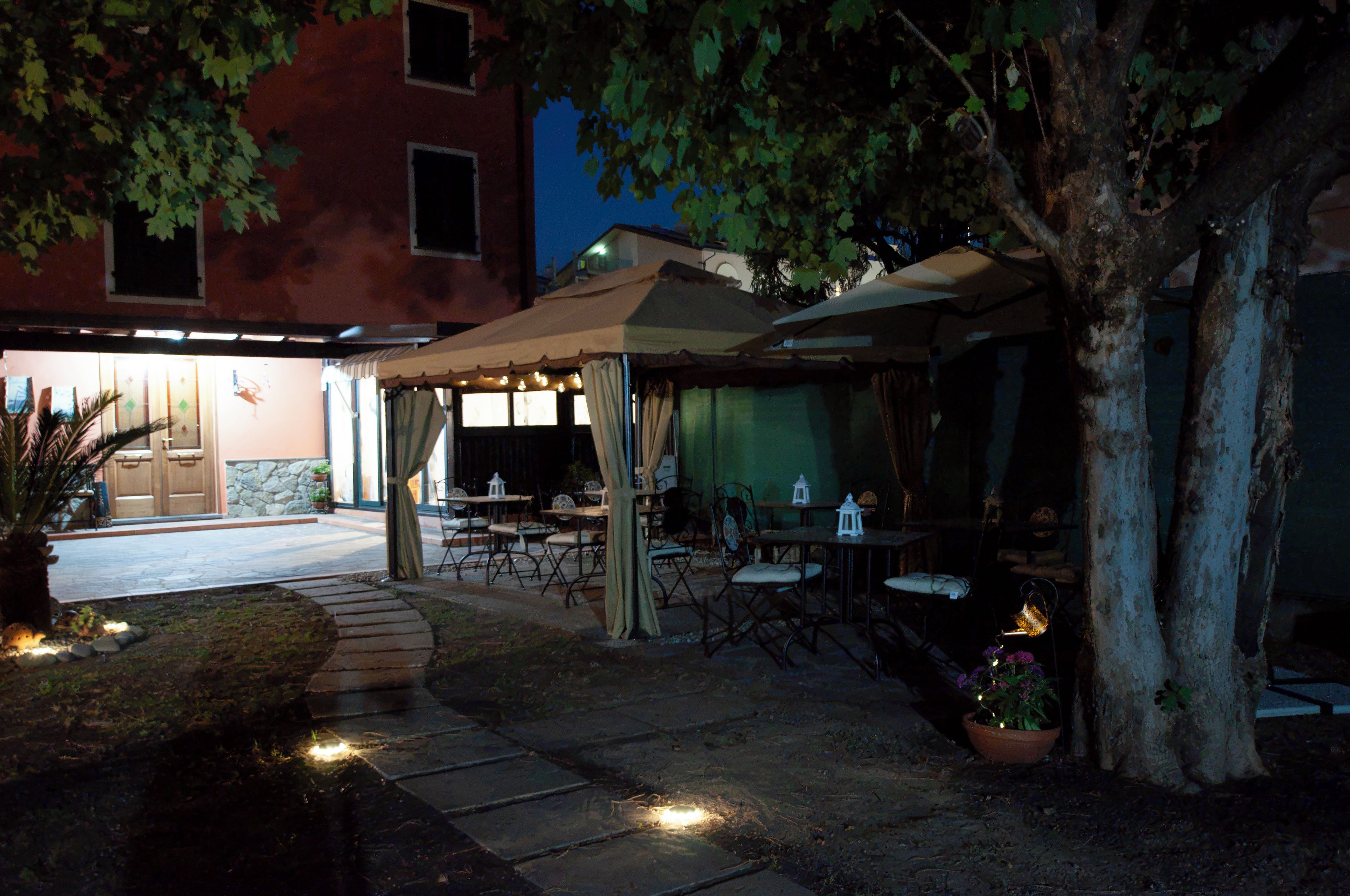Un patio al aire libre con mesas y sillas, un área de estar cubierta y un edificio en el fondo.