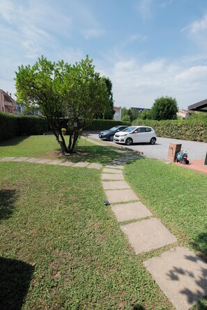Zona residencial con un sendero pavimentado que conduce a un camino de entrada donde hay coches estacionados.