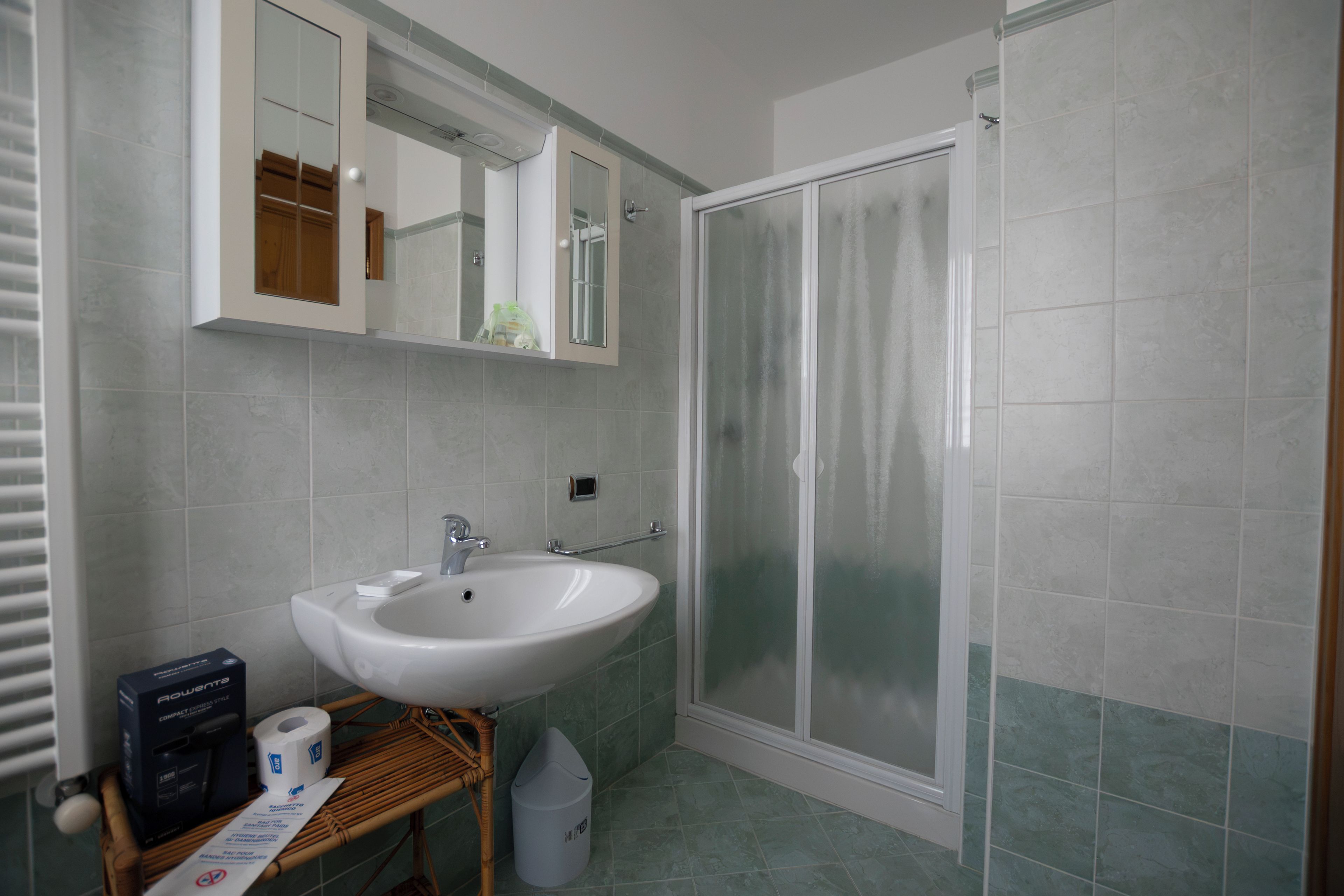 Une salle de bain avec un lavabo blanc, un miroir, un espace douche et des toilettes.