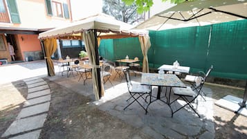 Un patio al aire libre con mesas y sillas, un espacio de estar techado y un sendero de piedra.