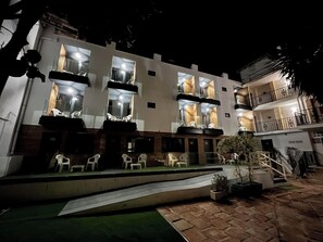 A multi-story hotel with balconies, outdoor seating, and a well-lit entrance. - Villa Albero (Torremolinos)