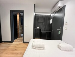 A hotel room with a bed, a desk, a television, and an air conditioning unit. - Villa Albero (Torremolinos)