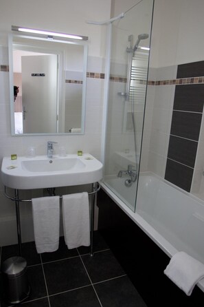 A bathroom with a white sink, mirror, and shower. There are two towels hanging on the wall. - Citotel Chartreuse (Cahors)