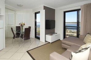 A modern hotel room with a balcony, a dining area, and a flat-screen TV. - Windsurfer Resort (Gold Coast)