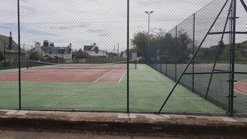 Ein durch einen Zaun gesäumter Tennisplatz mit Netz.