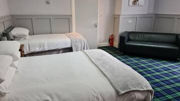 Ein Hotelzimmer mit zwei Betten, einer Couch, einem Feuerlöscher und einer Tür.