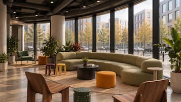 A modern lounge area with a large sectional sofa, round coffee table, and wooden chairs.