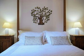 A hotel room with a bed, two nightstands, two lamps, and a wall decoration of a tree. - Cottage surrounded by a romantic garden (Gubbio)