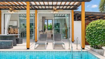 A poolside area with lounge chairs, a covered seating area, and a view of the interior through glass doors.