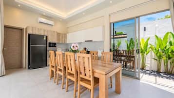 Cocina moderna con horno empotrado, microondas y comedor con mesa y sillas de madera.