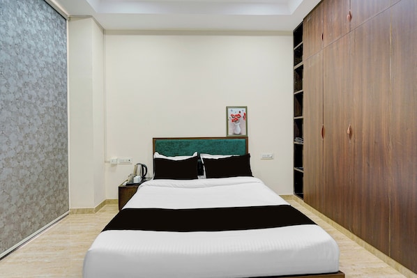 Una habitación de hotel con una cama, una mesita de noche, un armario de madera y un cuadro en la pared.