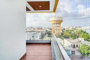 A balcony with a view of a cityscape, including a water tower and various buildings. - Palette Mansarover Extension (Jaipur)