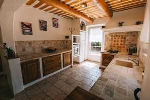 A kitchen with wooden cabinets, a tiled backsplash, and a stone countertop. - Villa 'Maison Lioux Parc Du Luberon' with Private Terrace, Private Garden and Wi-Fi (Lioux)