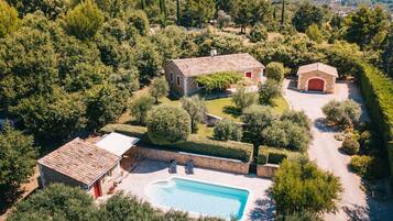 A property with a swimming pool, two stone buildings, and a surrounding garden.