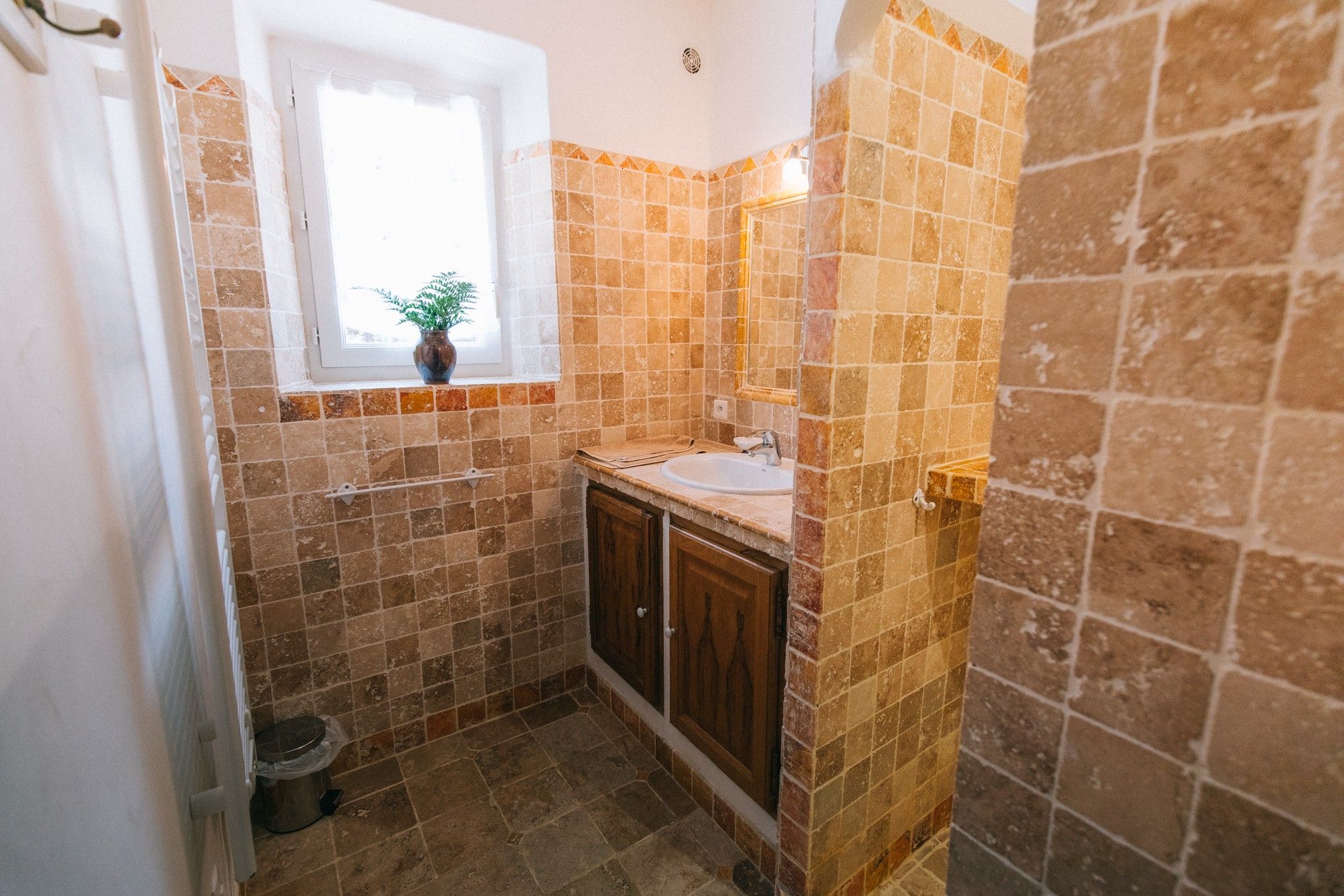 A small bathroom with a window, a sink, and a mirror.