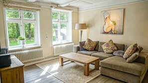 Ein Wohnzimmer mit Sofa, Couchtisch, Lampe und einem Gemälde.