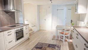 Eine moderne Küche mit weißen Schränken, einem eingebauten Backofen und einer Edelstahl-Dunstabzugshaube.
