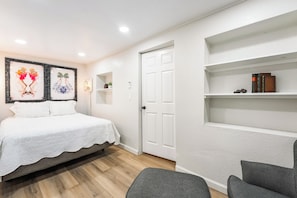 A bedroom with a bed, a door, a shelf with books, and a framed artwork on the wall. - Prime Dwntwn Location|Fully Private La Casita (Las Vegas)
