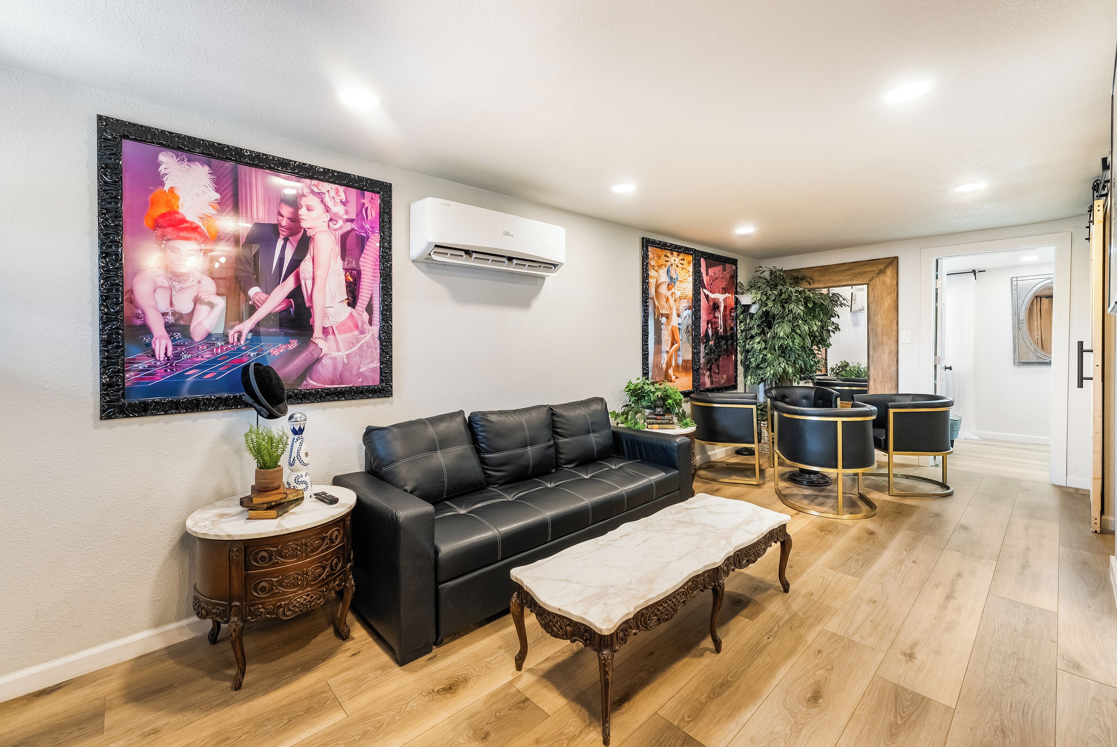 A modern living room with a black leather sofa, a marble coffee table, and a large framed artwork on the wall.