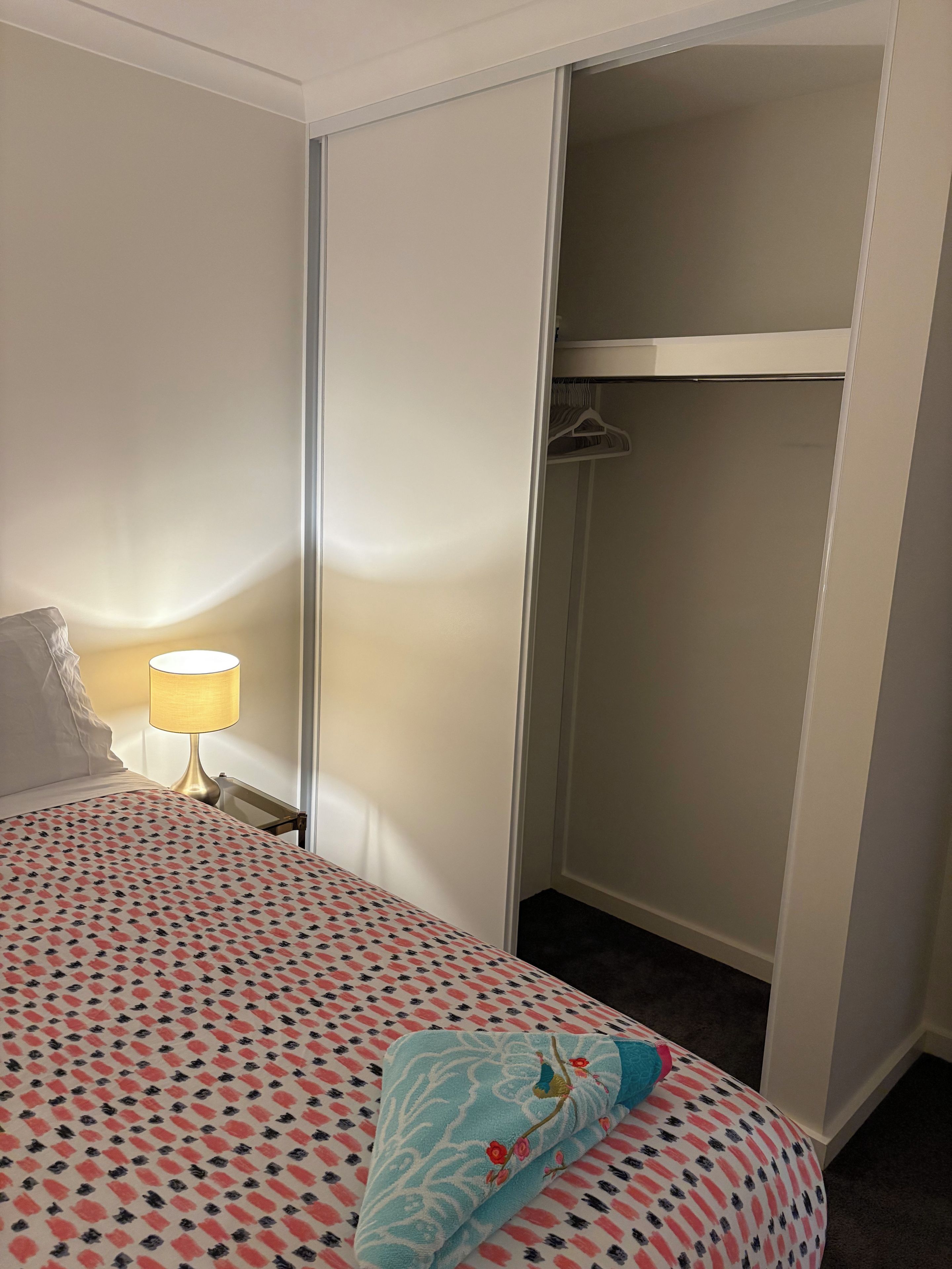 Quarto de hotel com cama, luminária de cabeceira, guarda-roupa e closet.