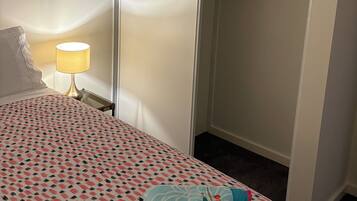 Quarto de hotel com cama, luminária de cabeceira, guarda-roupa e closet.